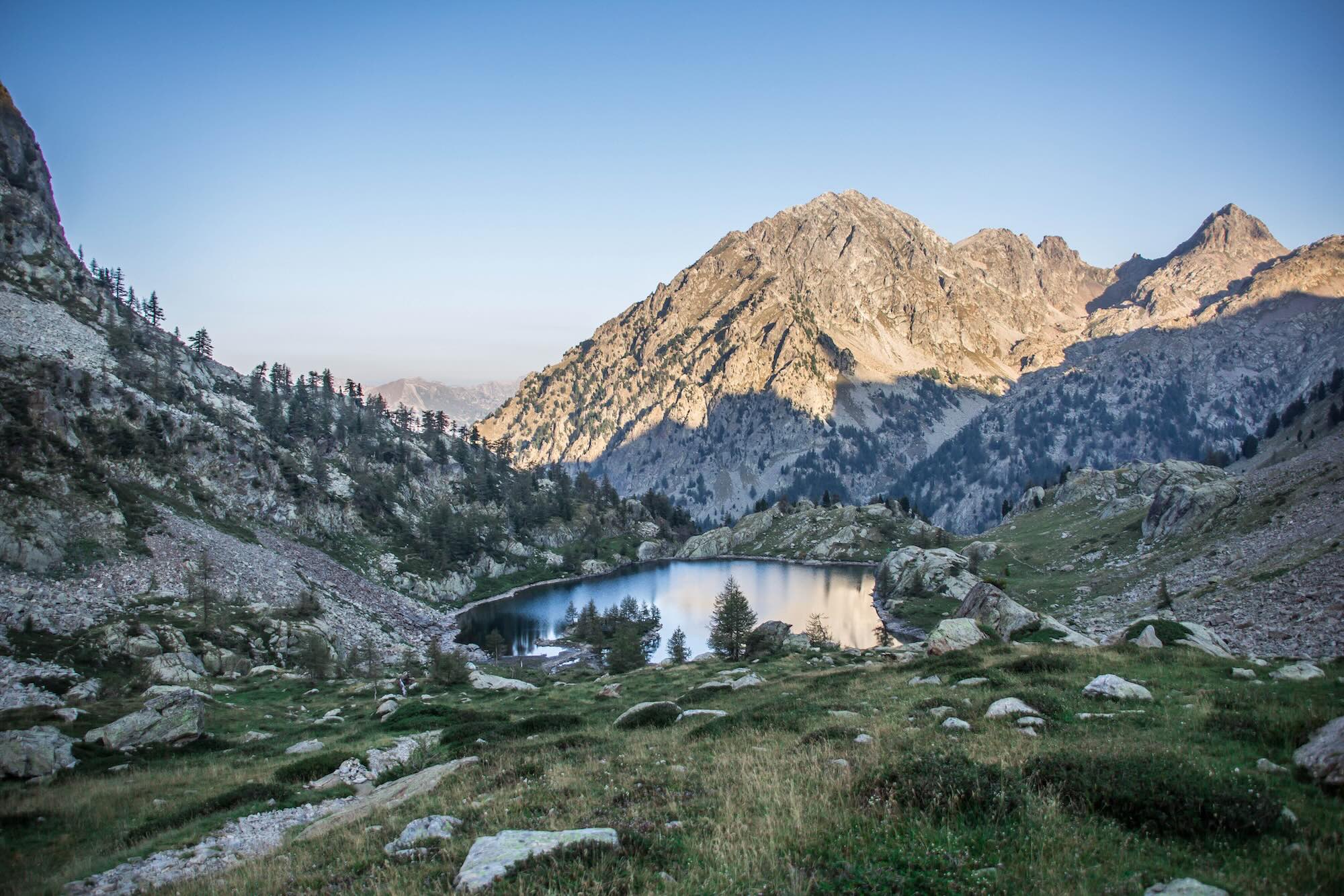 Lac alpin du Mercantour entre sommets rocheux sous un ciel bleu clair