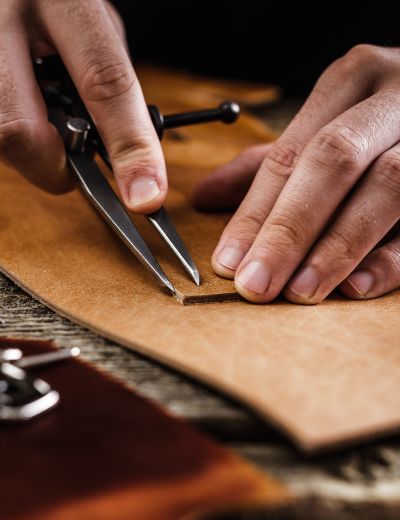 Maroquinier marquant une pièce de cuir au compas dans son atelier